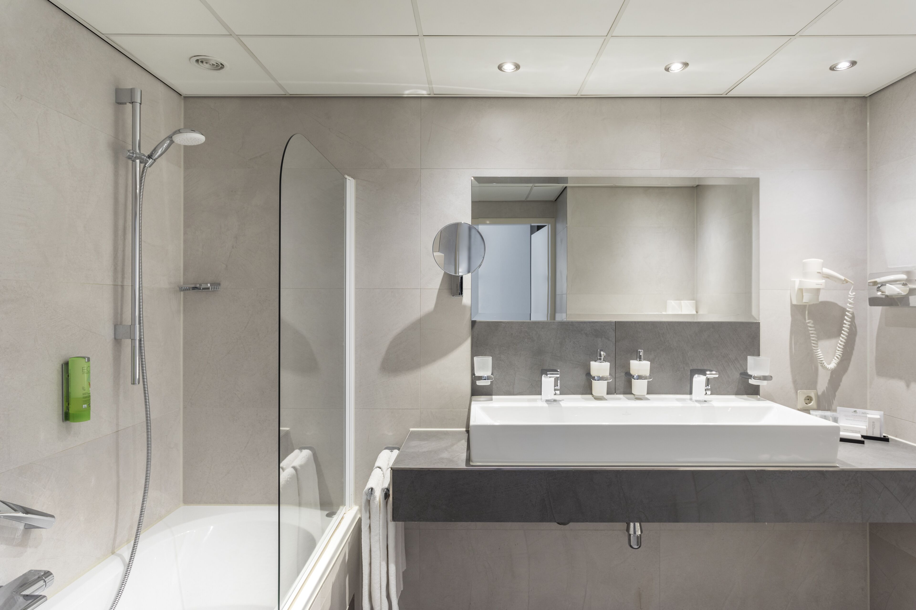 A modern bathroom with a glass-enclosed shower, a large mirror, and a dual sink vanity.