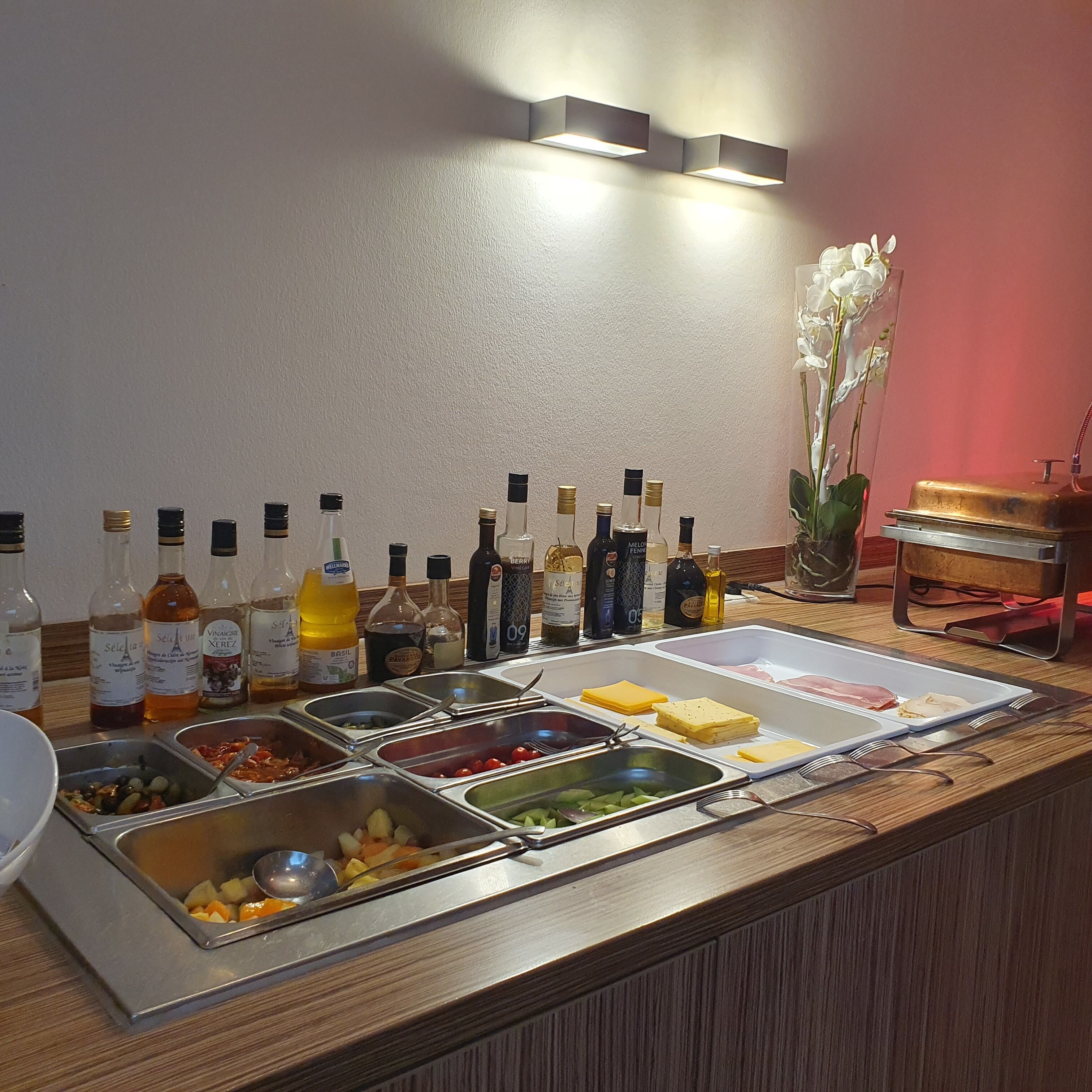 Una mesa de buffet con diversos alimentos y aderezos.