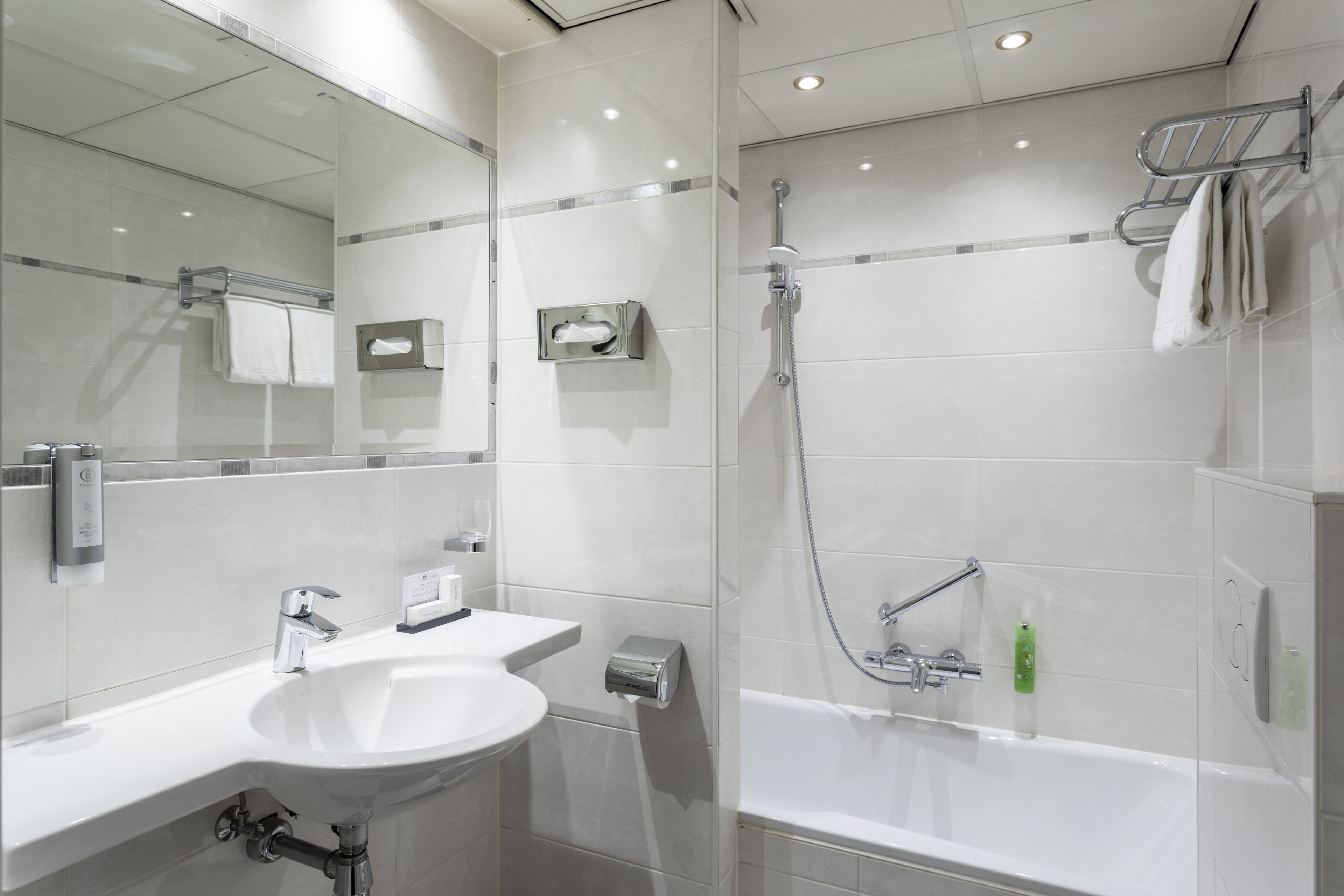 A modern bathroom with a sink, mirror, towel rack, and shower.