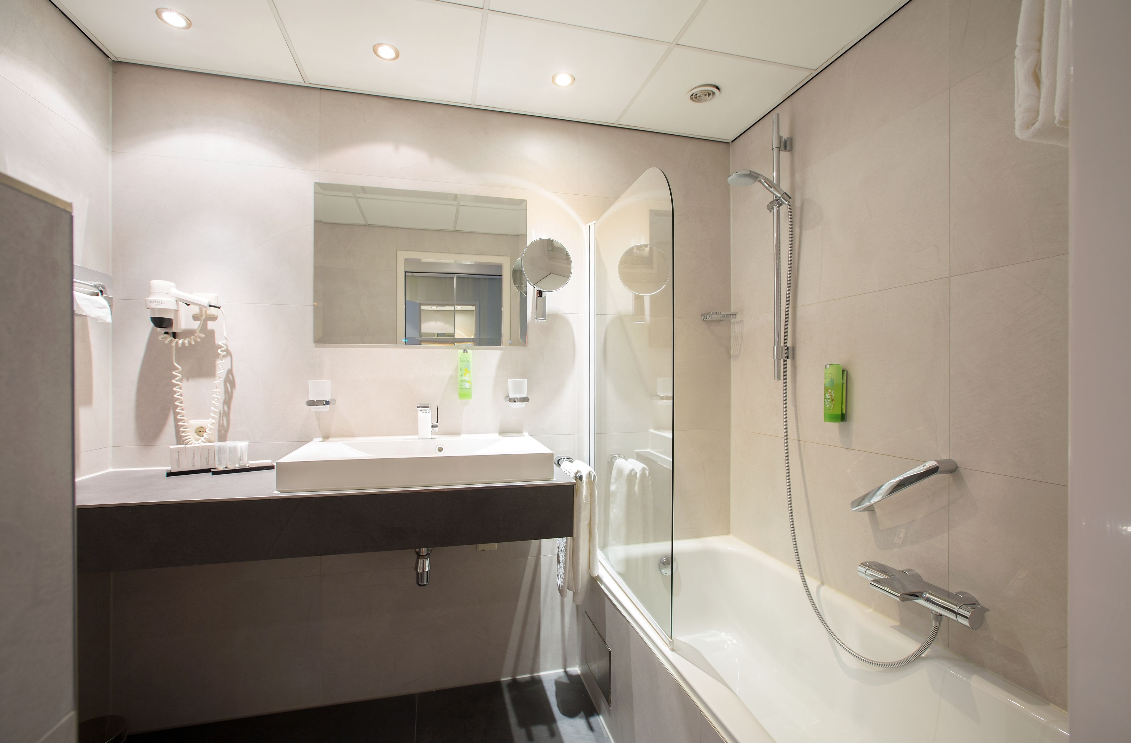 A modern bathroom with a large mirror, a sink, and a glass-enclosed shower area.