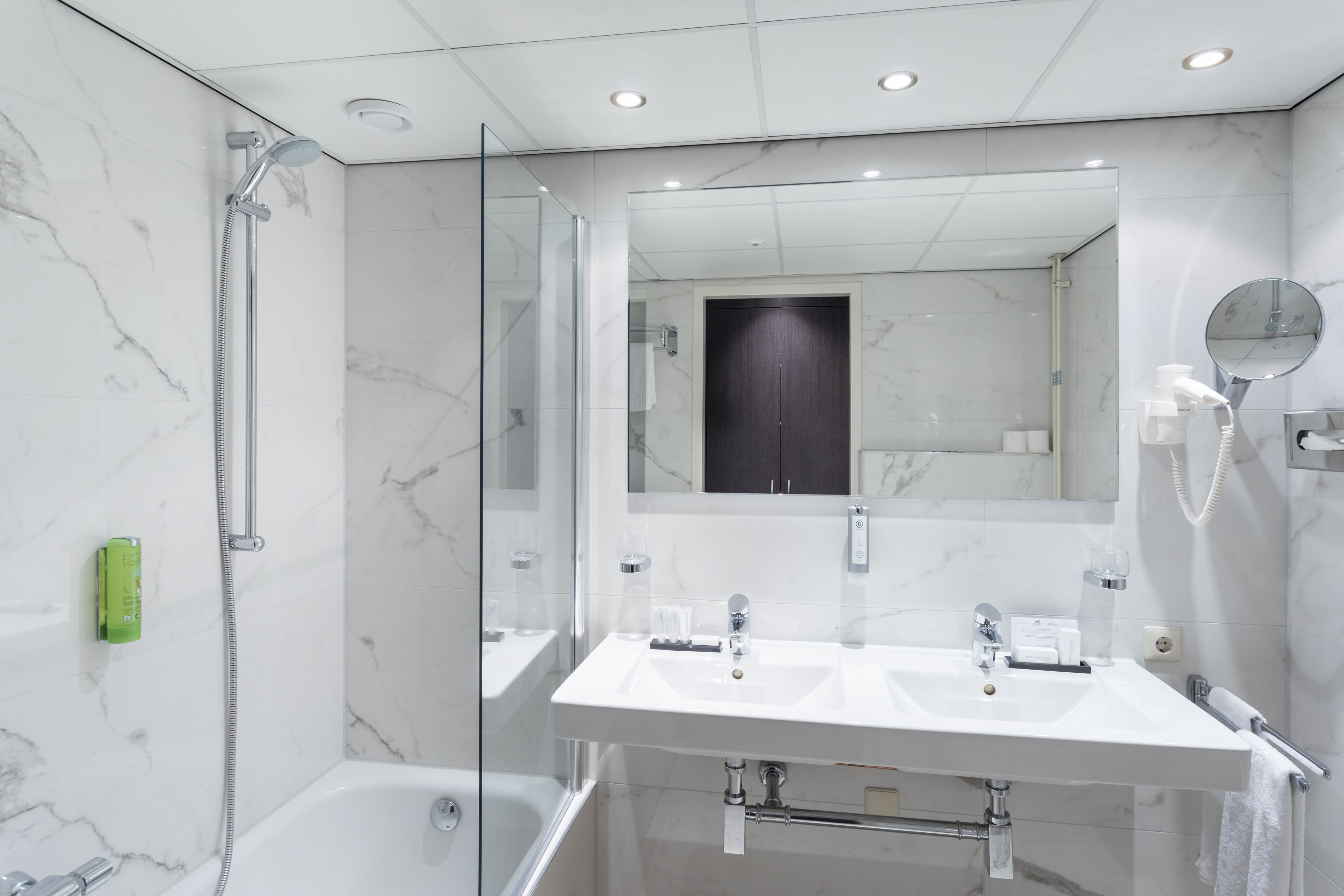 A modern bathroom with a glass-enclosed shower, a double sink vanity, and a large mirror.