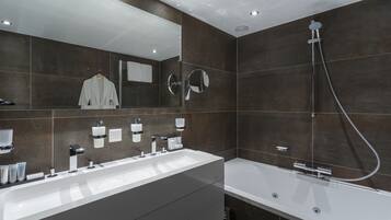 Un baño moderno con tocador doble lavamanos, un espejo grande, cabezal de ducha de mano y una bañera independiente.