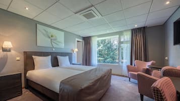 Una habitación de hotel con una cama grande, un escritorio y dos sillones.