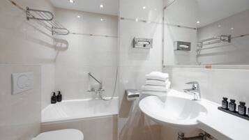 A modern bathroom with a white toilet, a bathtub, a sink, and a mirror.