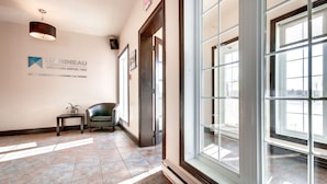 A hotel lobby with a large window, a chair, a small table, and a wall sign.