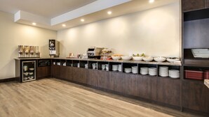 A modern kitchen with a built-in microwave, a coffee machine, and a variety of bowls and plates on the counter.