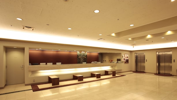 Un hall d’entrée spacieux avec un comptoir d’accueil, un espace détente et des ascenseurs.