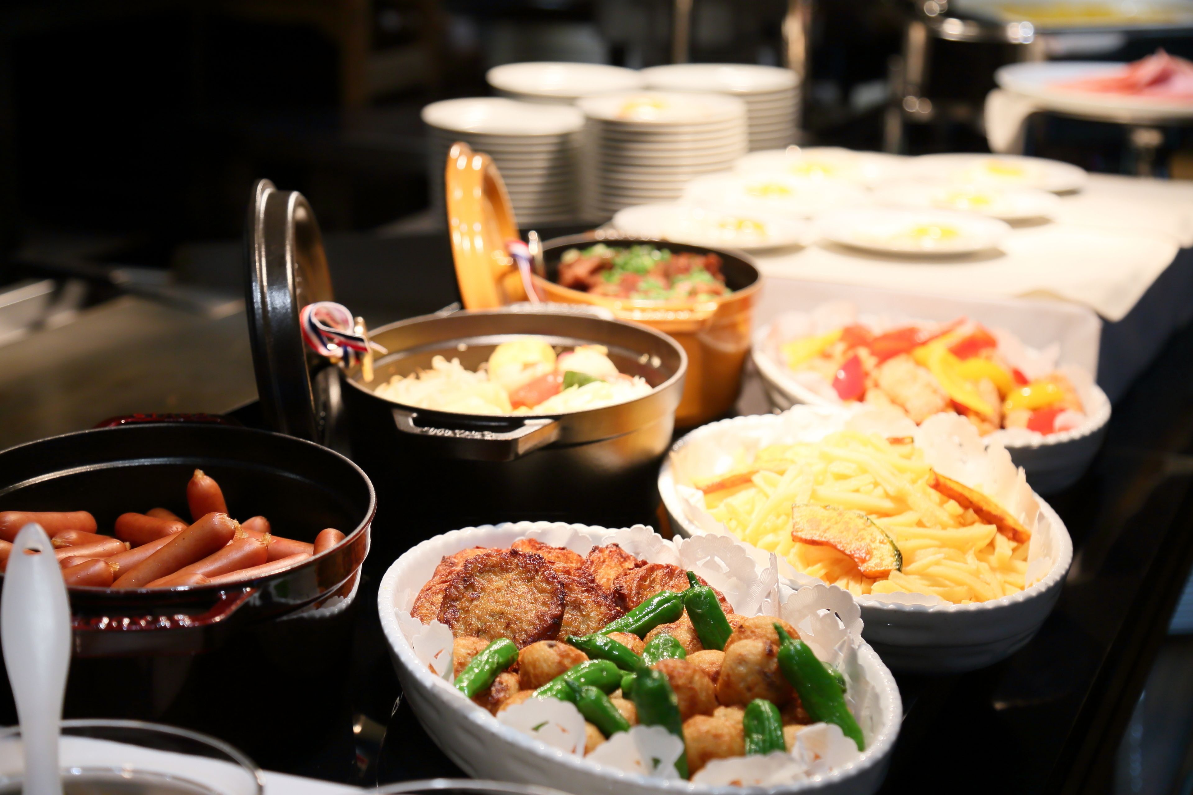 A buffet with various dishes including sausages, fried items, and salads.