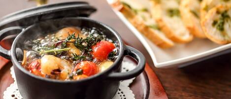 A black pot with a stew on a wooden table.
