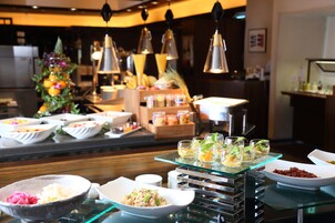A buffet with various dishes and drinks, including bowls of food and glasses with drinks.