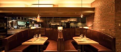 A restaurant with a booth seating arrangement, a wooden table, and pendant lighting.