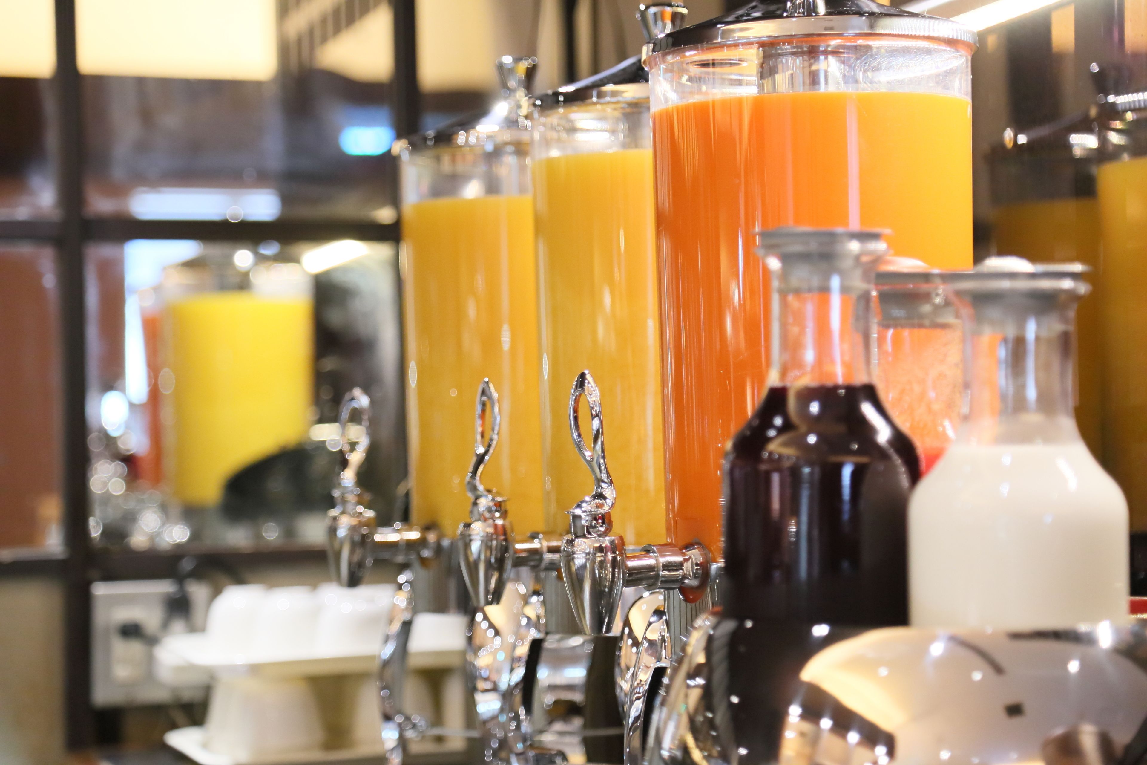 A bar area with multiple glass dispensers filled with orange juice.