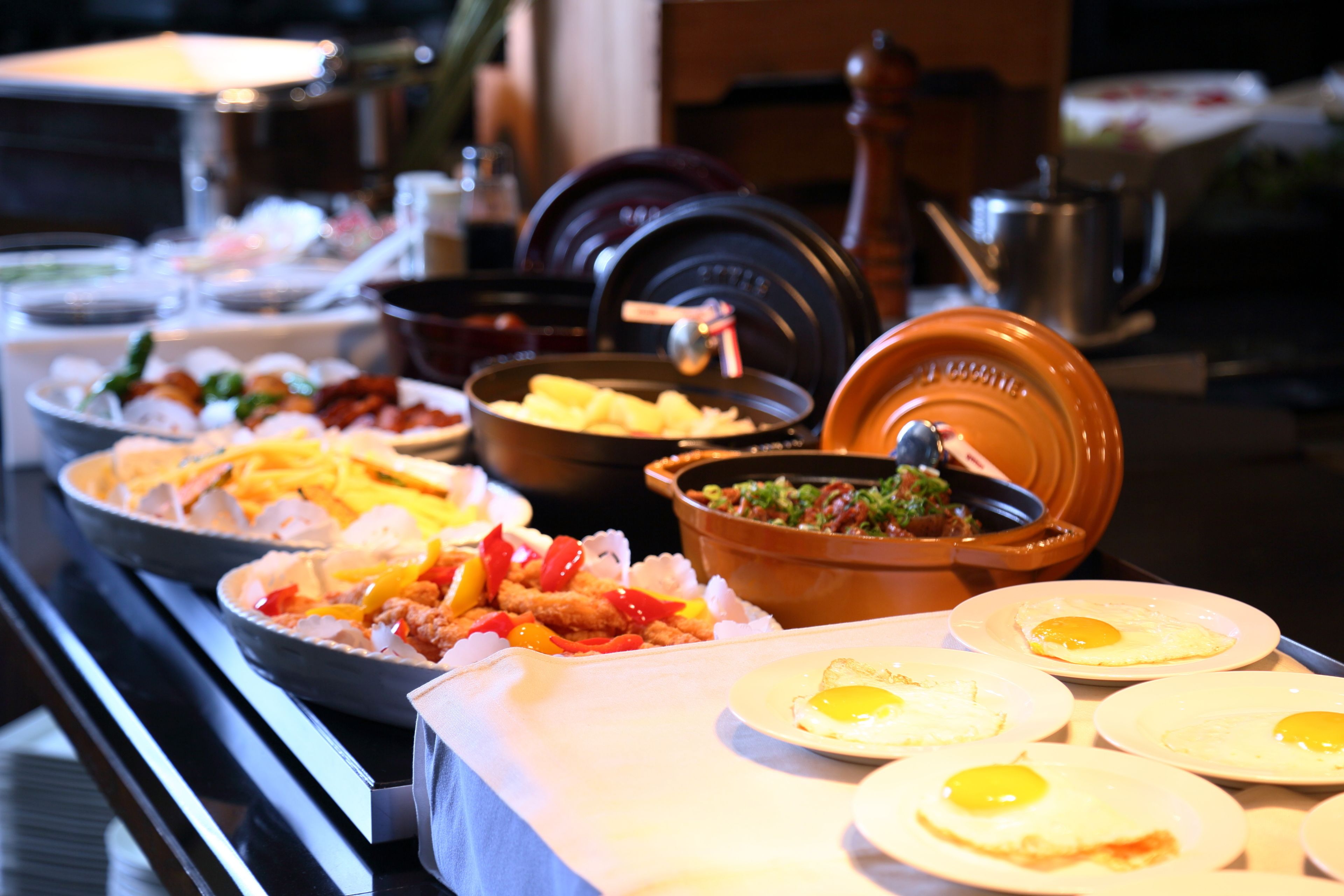 A buffet with various dishes including fried eggs, vegetables, and meats.