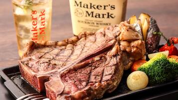 Un plato de carne con verduras y una botella de whisky bourbon Maker's Mark.