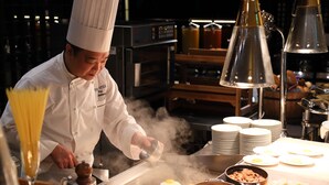 Un chef préparant des plats dans une cuisine équipée d’un gril, d’assiettes et de divers ustensiles de cuisine.