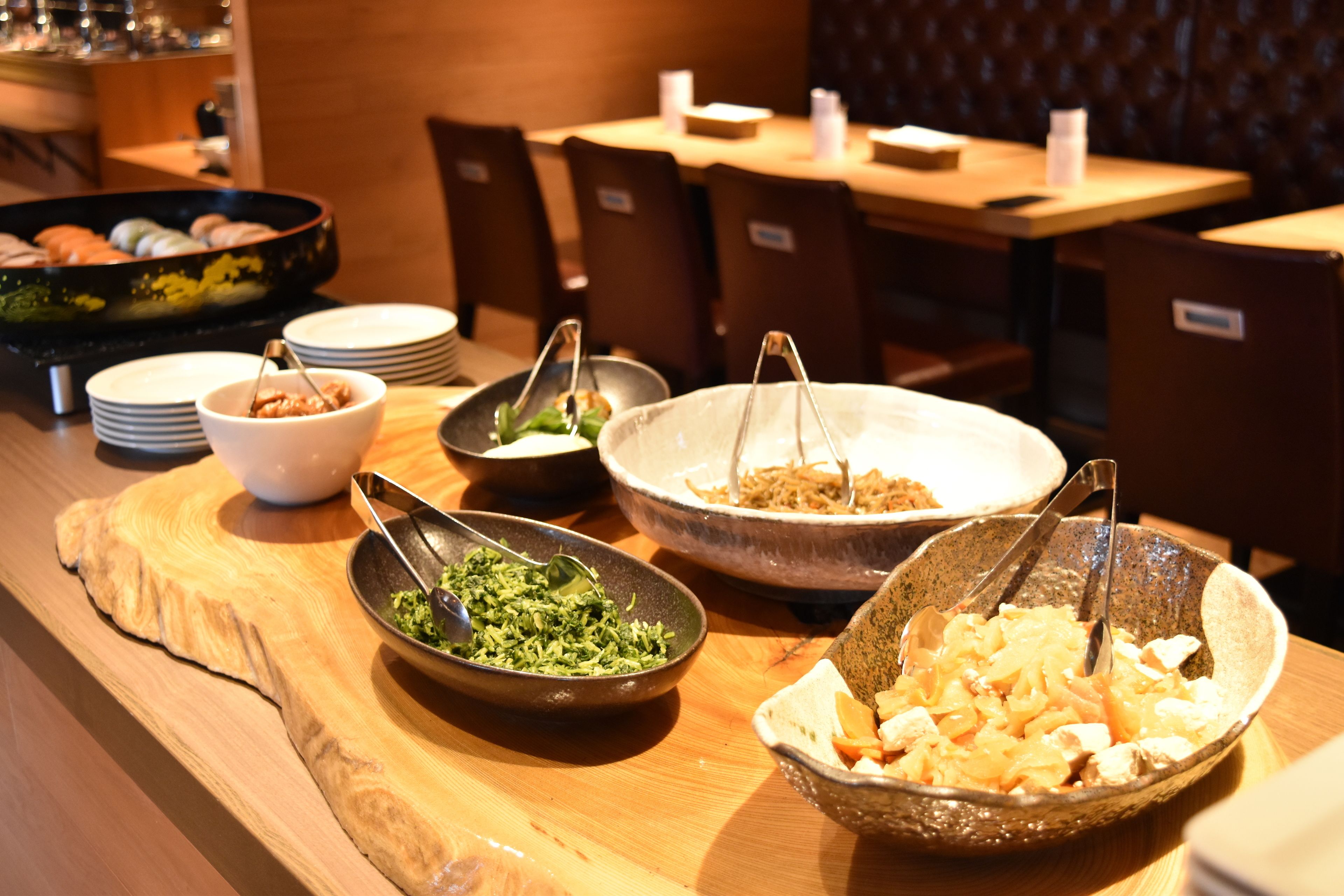 A buffet setup with various dishes and bowls on a wooden table.