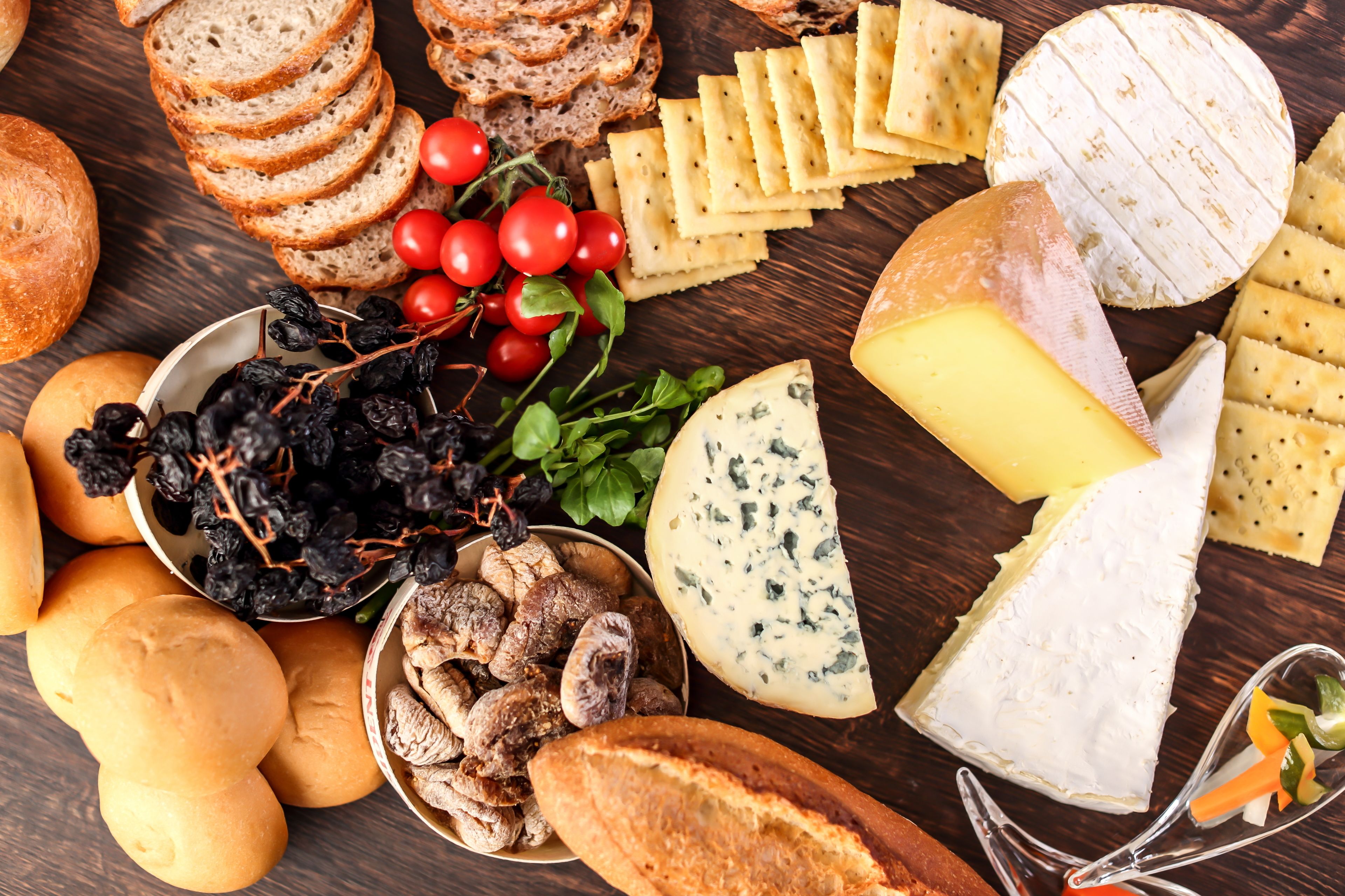 A variety of cheeses, crackers, and bread on a wooden table.