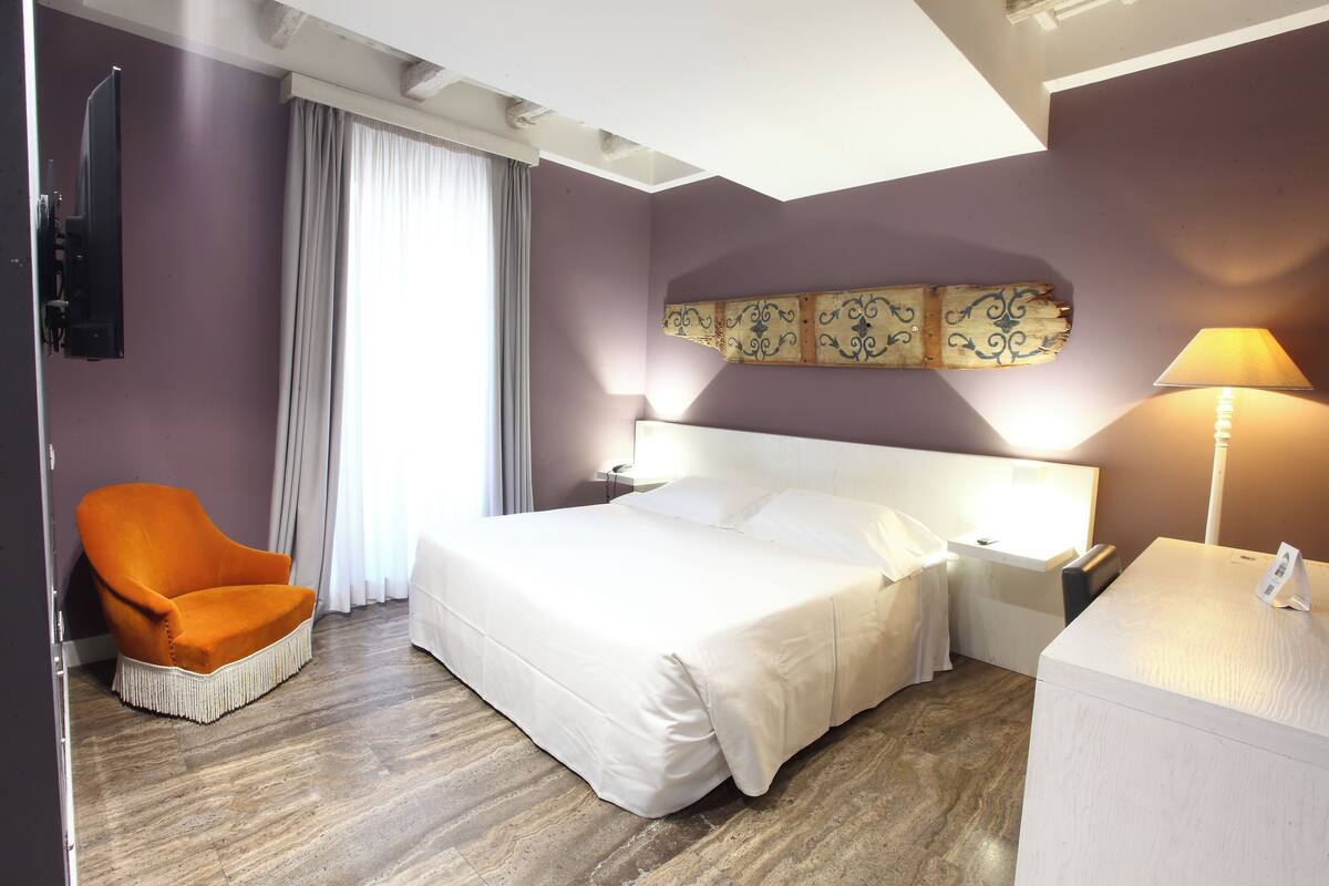 Une chambre d’hôtel avec un grand lit, une chaise, un bureau et une télévision.