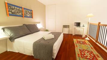 Una camera da letto ordinata con un letto, un comodino, una TV e un tappeto decorato.