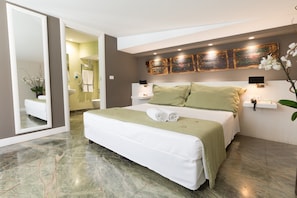 Un dormitorio moderno con una cama grande, una mesita de noche, un espejo y una obra de arte colgada en la pared.
