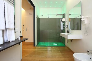 Un baño moderno con ducha de vidrio, lavabo blanco y espejo.