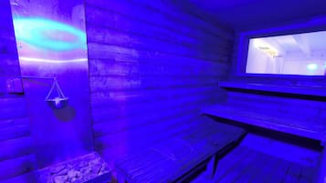 Un sauna avec des murs en bois, un banc et un bassin en pierre.