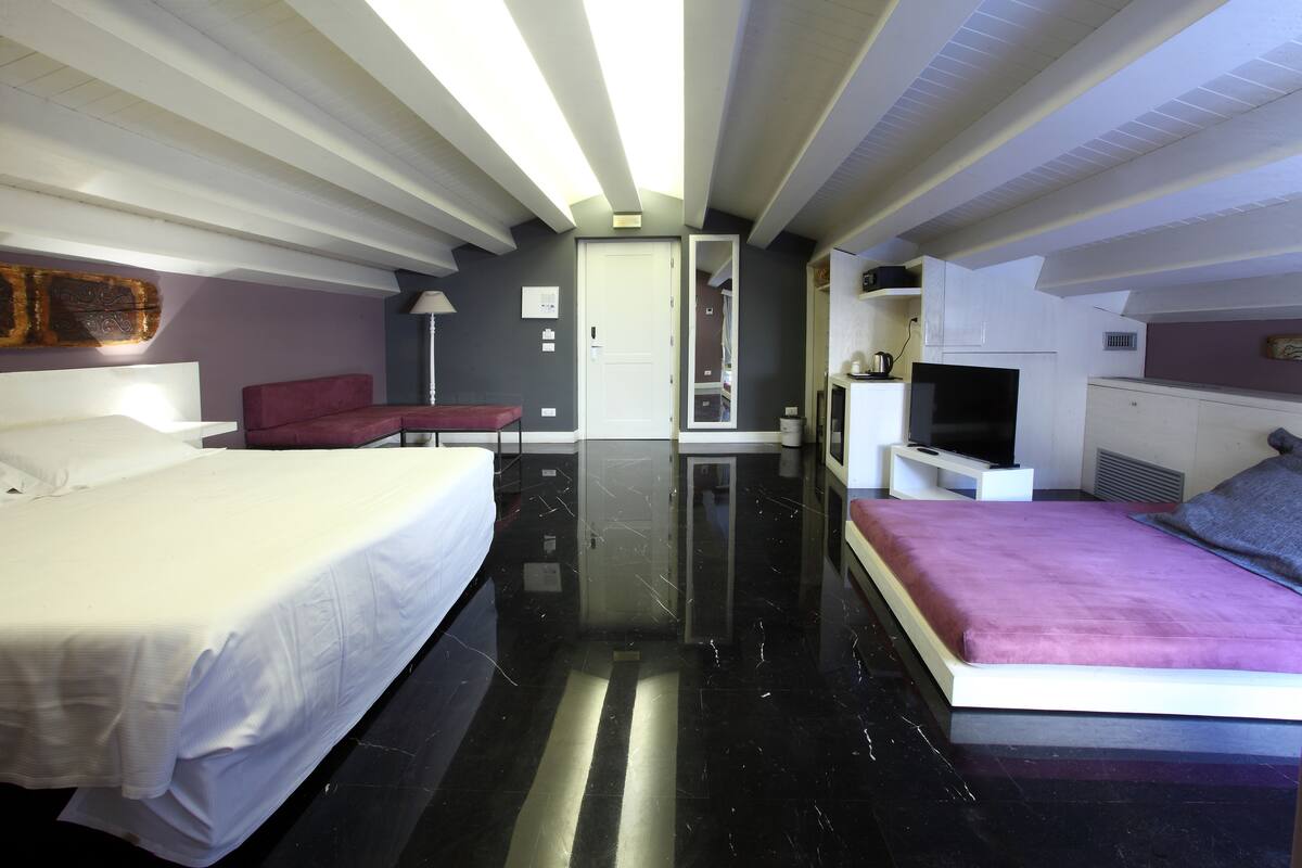 Une chambre d’hôtel moderne équipée d’un grand lit, d’un lit plus petit, d’une télévision et d’un coin salon.