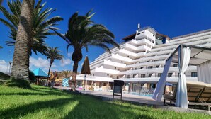 A modern hotel with multiple floors, outdoor pool, and palm trees. - Hotel Chatur Palmera Mar (Mogan)