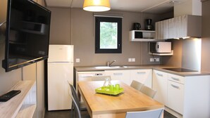 A compact kitchen with white appliances, a wooden dining table, and a window above the sink.