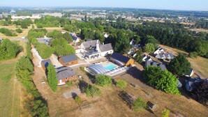 An aerial view of a residential area with houses, a swimming pool, and surrounding greenery.