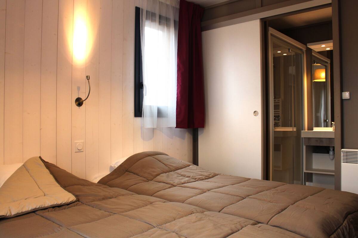 Une chambre à coucher avec un lit, une fenêtre avec des rideaux et une porte donnant sur une salle de bain.