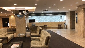 A lobby with a reception desk, seating area, and a clock on the wall. - Narita U-City Hotel (Narita)