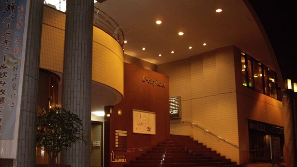 A building with a curved facade, a staircase leading to an upper level, and a sign with Japanese characters. - Narita U-City Hotel (Narita)