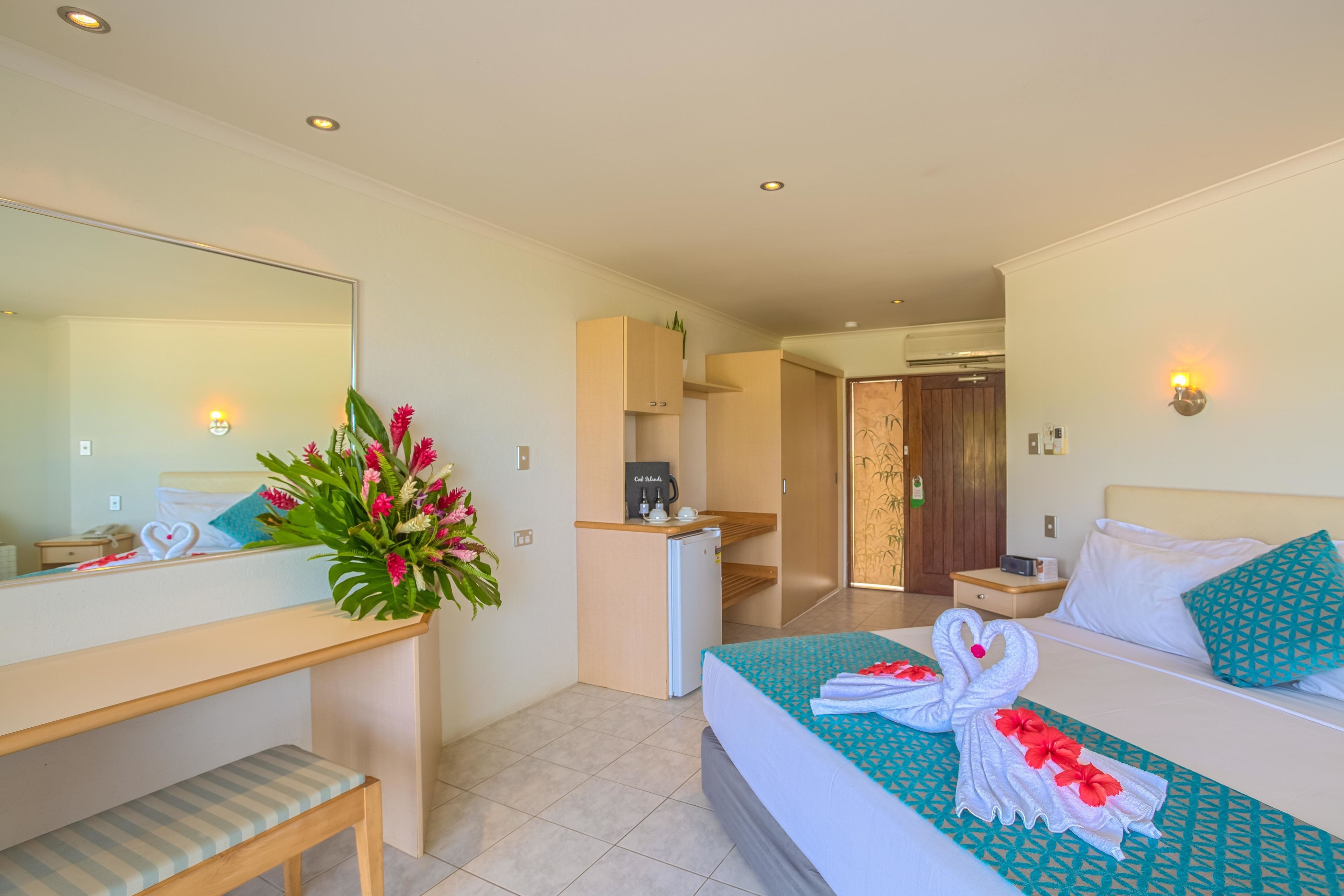 A hotel room with a bed, a desk, a small kitchenette, and a bathroom.