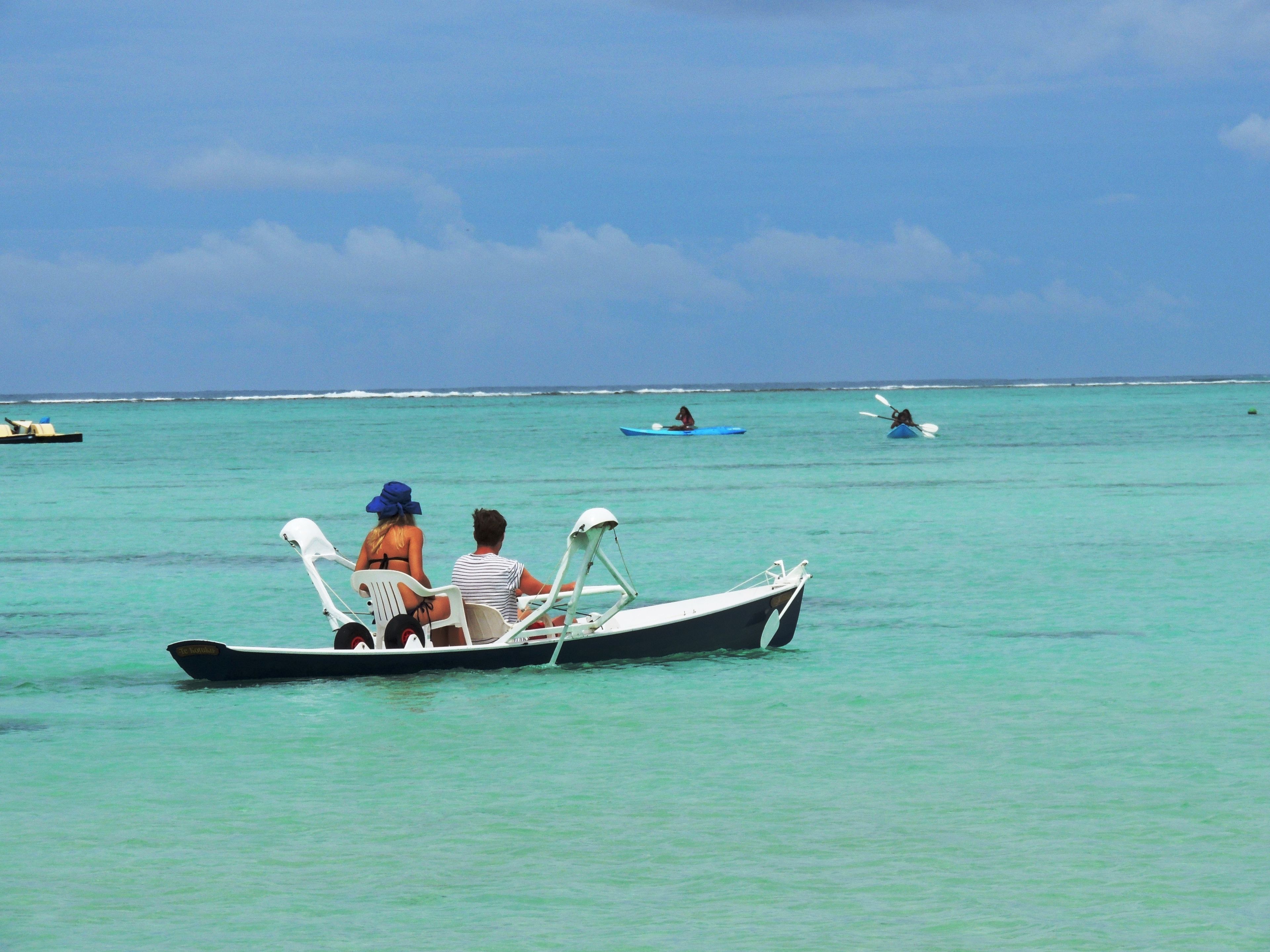 Un petit bateau avec deux personnes à bord, naviguant sur une eau turquoise et cristalline.