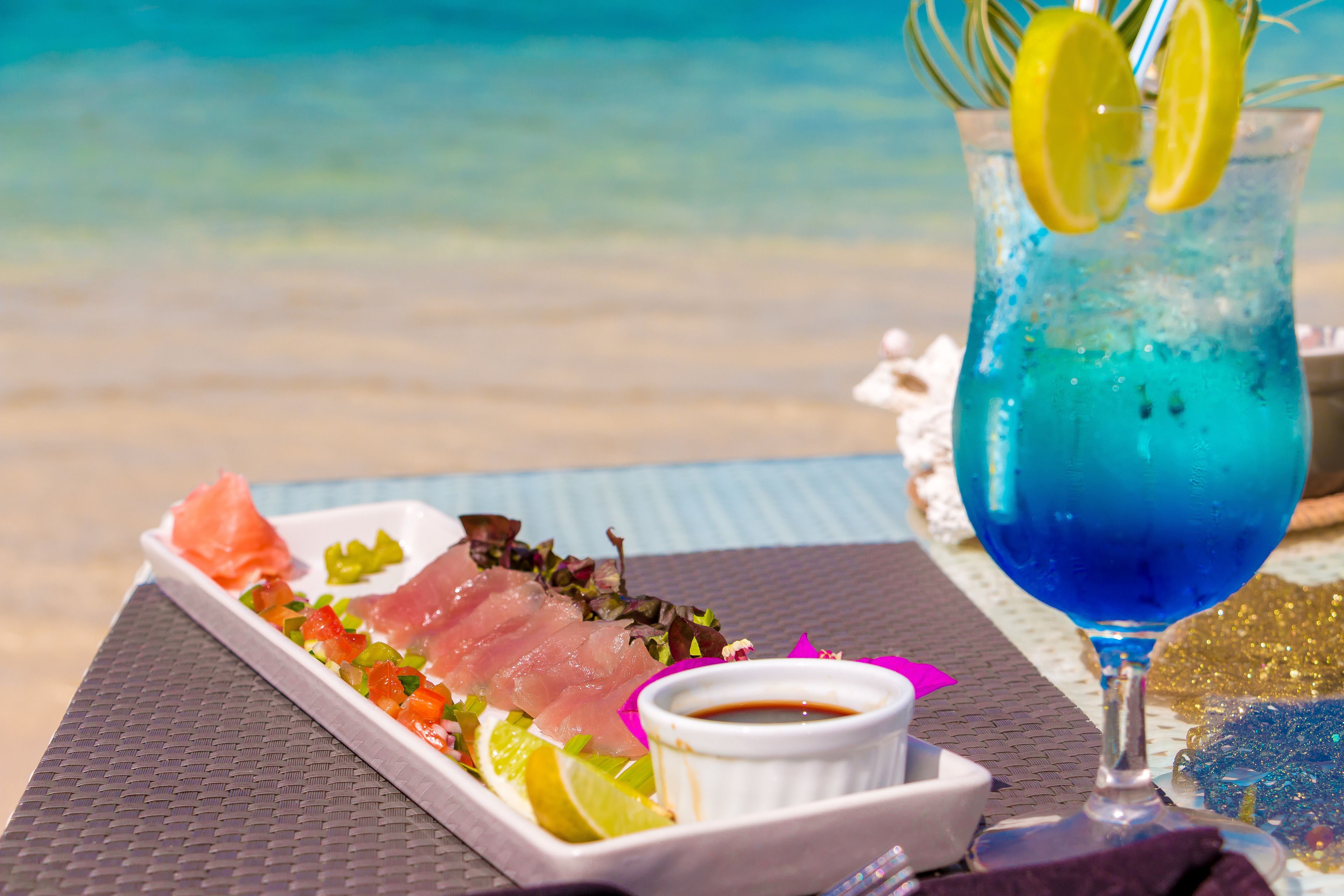 A seafood platter with a drink on a table by the beach.