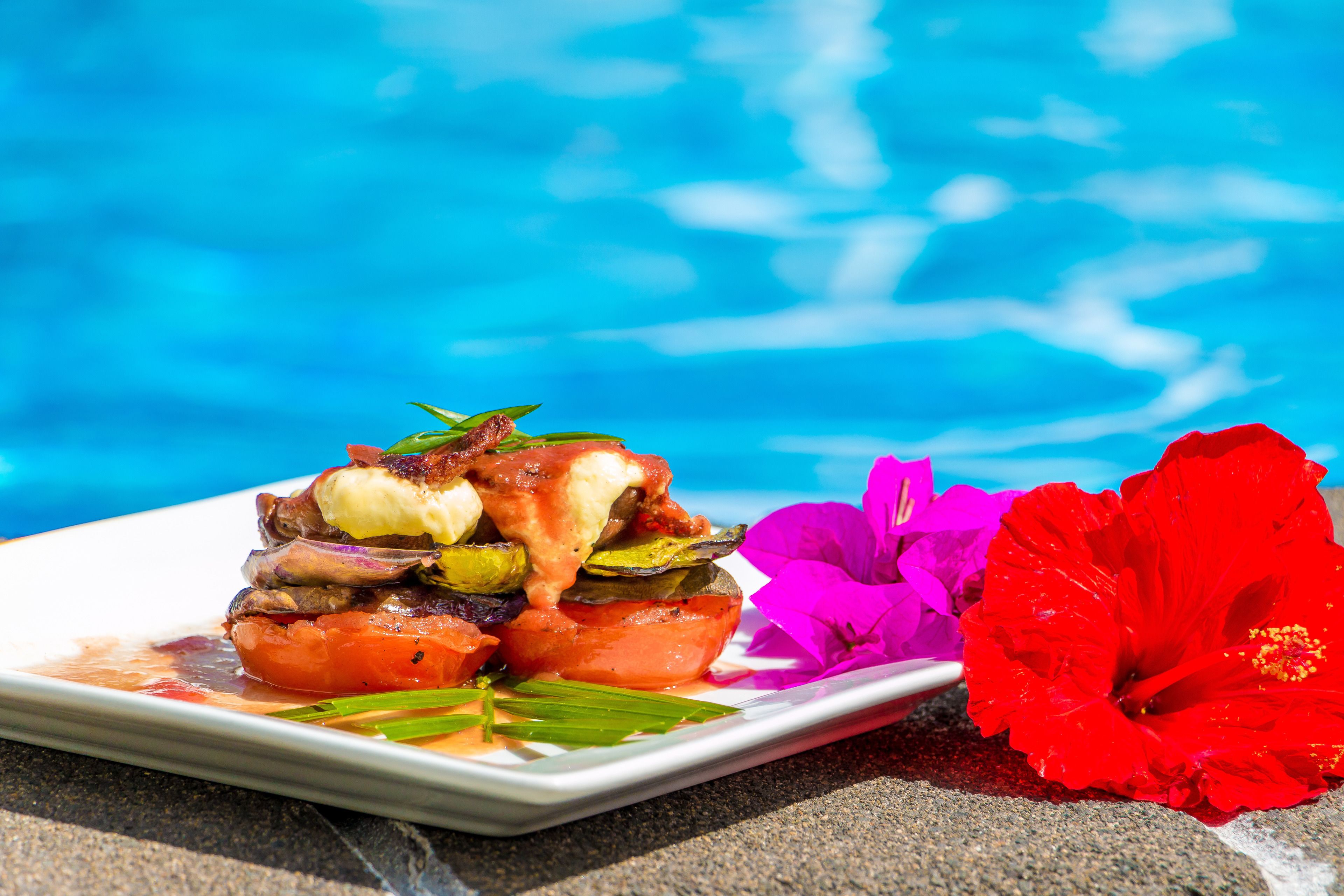A plate of food with vegetables and a hibiscus flower.