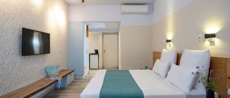 A modern hotel room with a bed, a bench, a TV, and a small table with a vase.