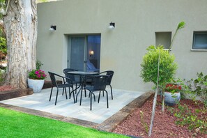 Une terrasse avec une table et des chaises, un pot de fleurs et un arbre.