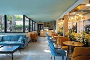 Un interior moderno con sofá, sillones, mesas y una zona de bar.