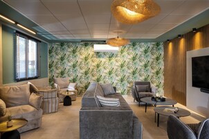 Una sala de estar moderna con un sofá modular, sillones, una mesa de centro y un televisor montado en la pared.