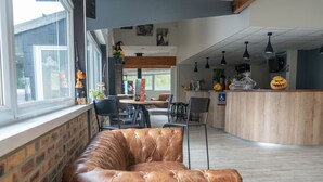 Un interior moderno con un sofá de cuero, mesas de madera y plantas en macetas.