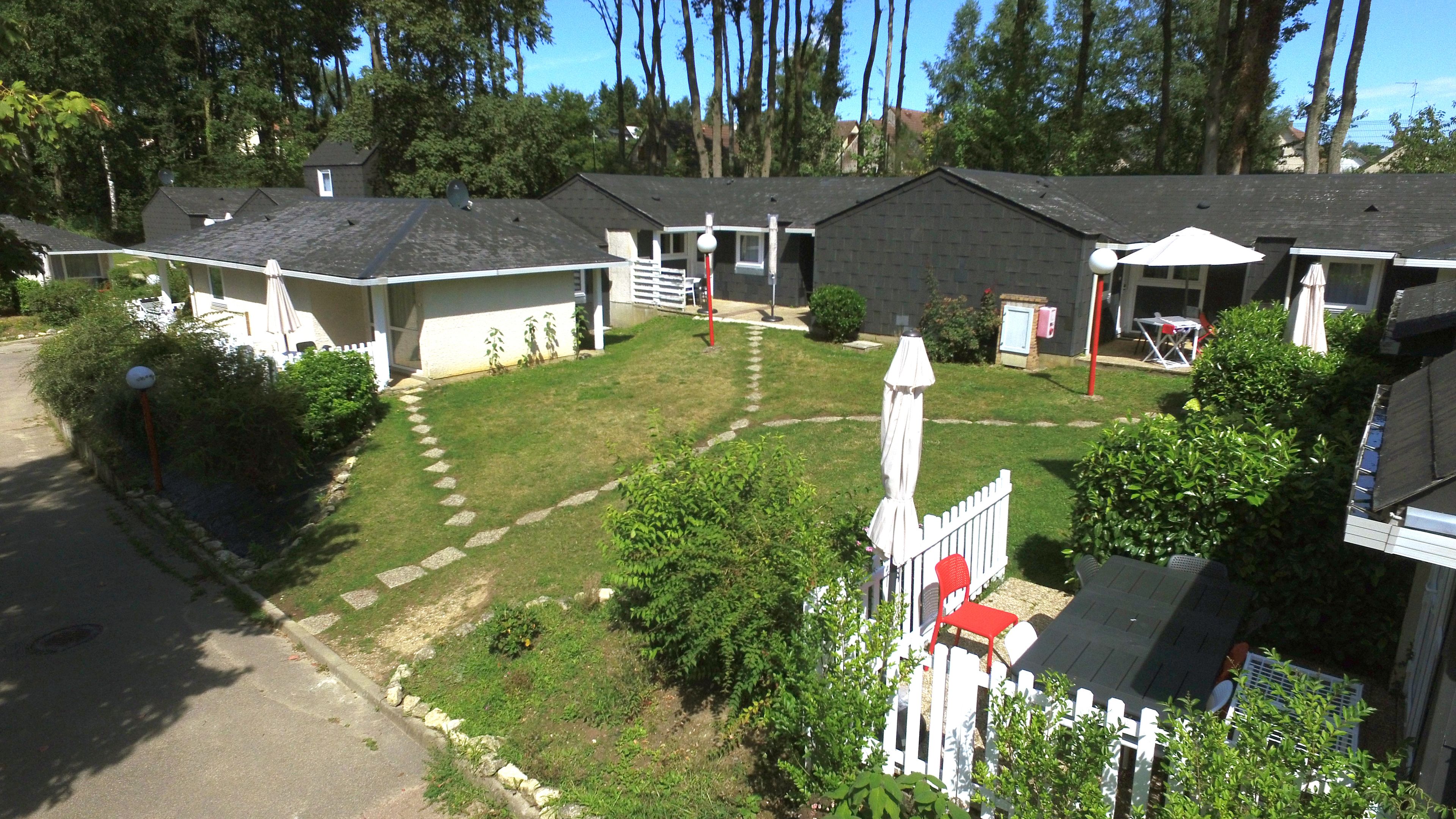 A residential area with multiple houses, a well-maintained lawn, and a white picket fence.