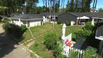 A residential area with multiple houses, a well-maintained lawn, and a white picket fence.