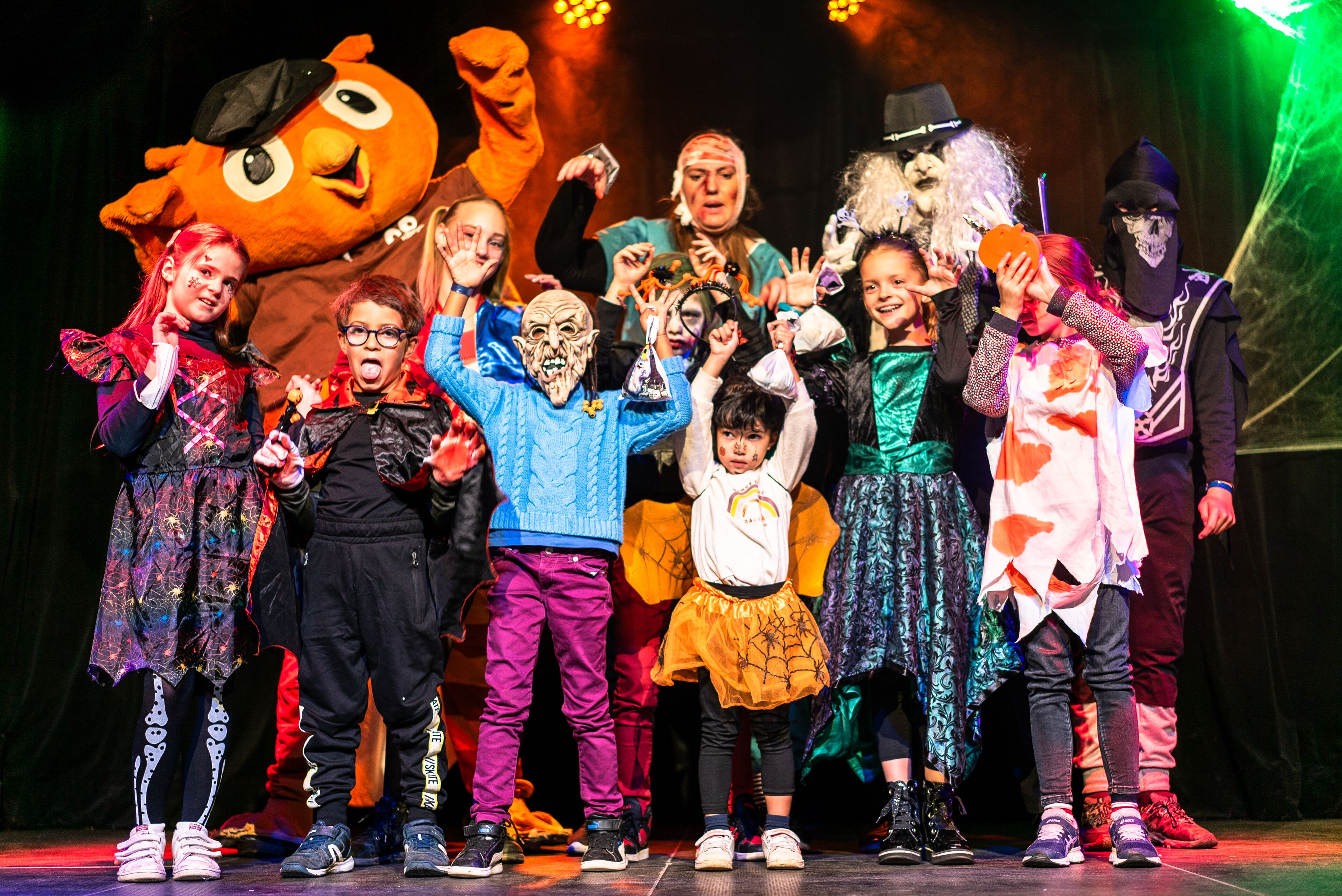 A group of people on a stage with a large mascot and various costumes.