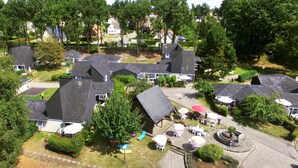 Un barrio residencial con varias casas, algunas con techos inclinados, rodeado de vegetación y árboles.