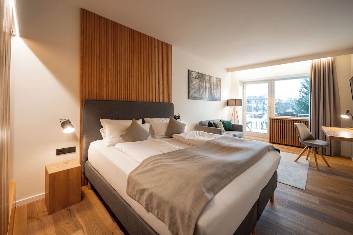Habitación de hotel moderna con una cama grande, un escritorio, una silla y vistas al exterior.