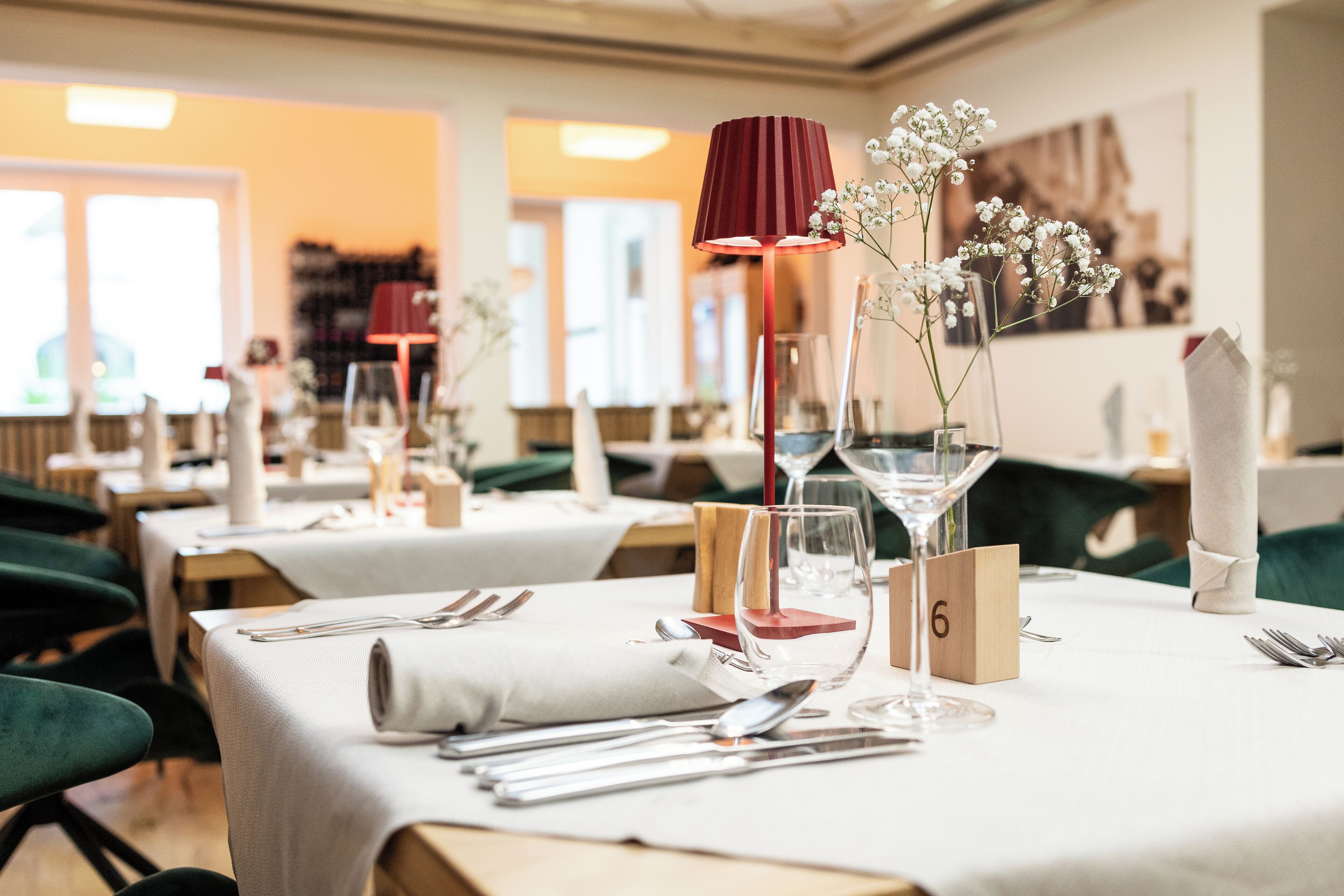 Ein Restaurant mit gedeckten Tischen, nummerierten Platzkarten und einer roten Lampe.