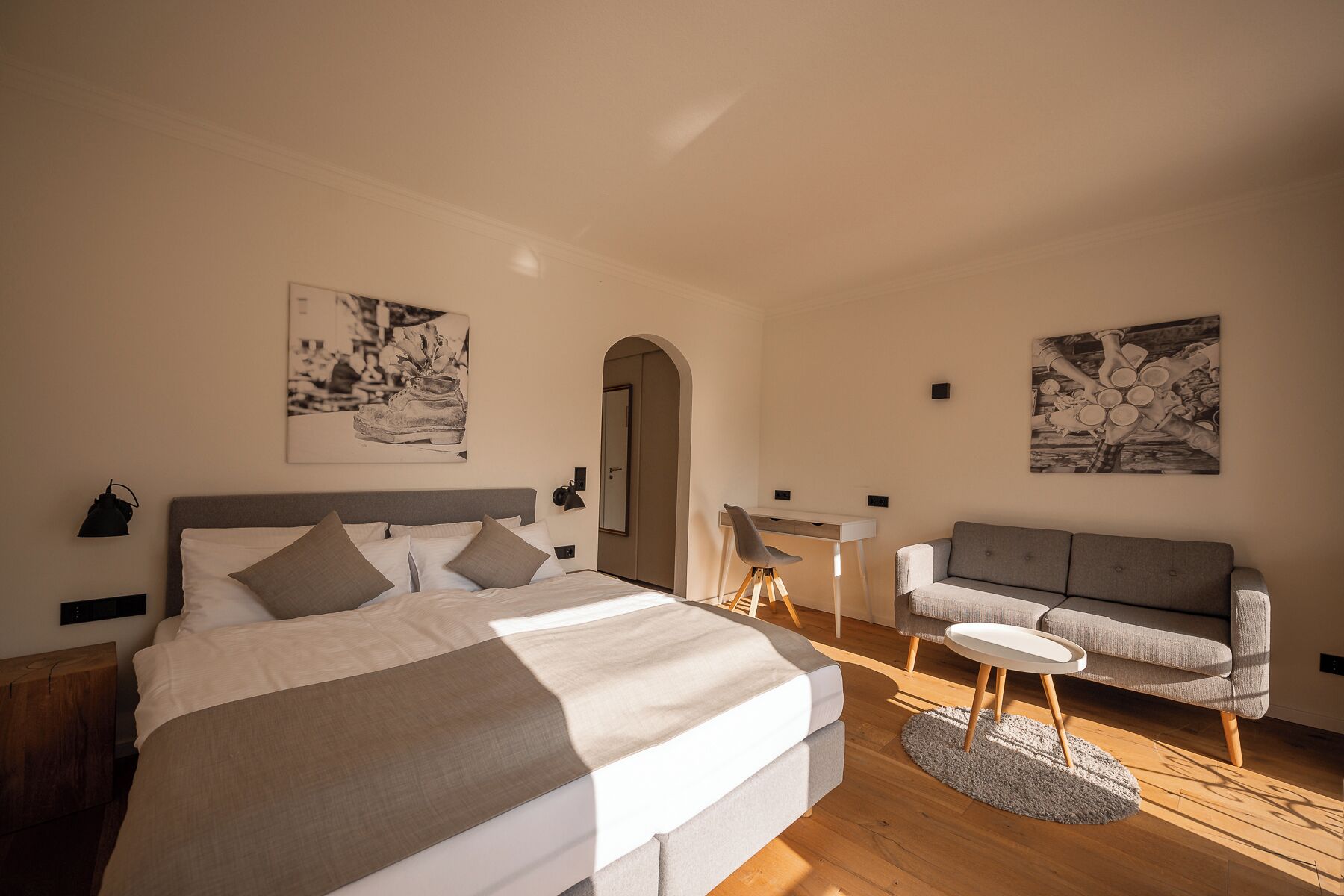 A bedroom with a bed, a desk, a chair, and two wall-mounted artworks.