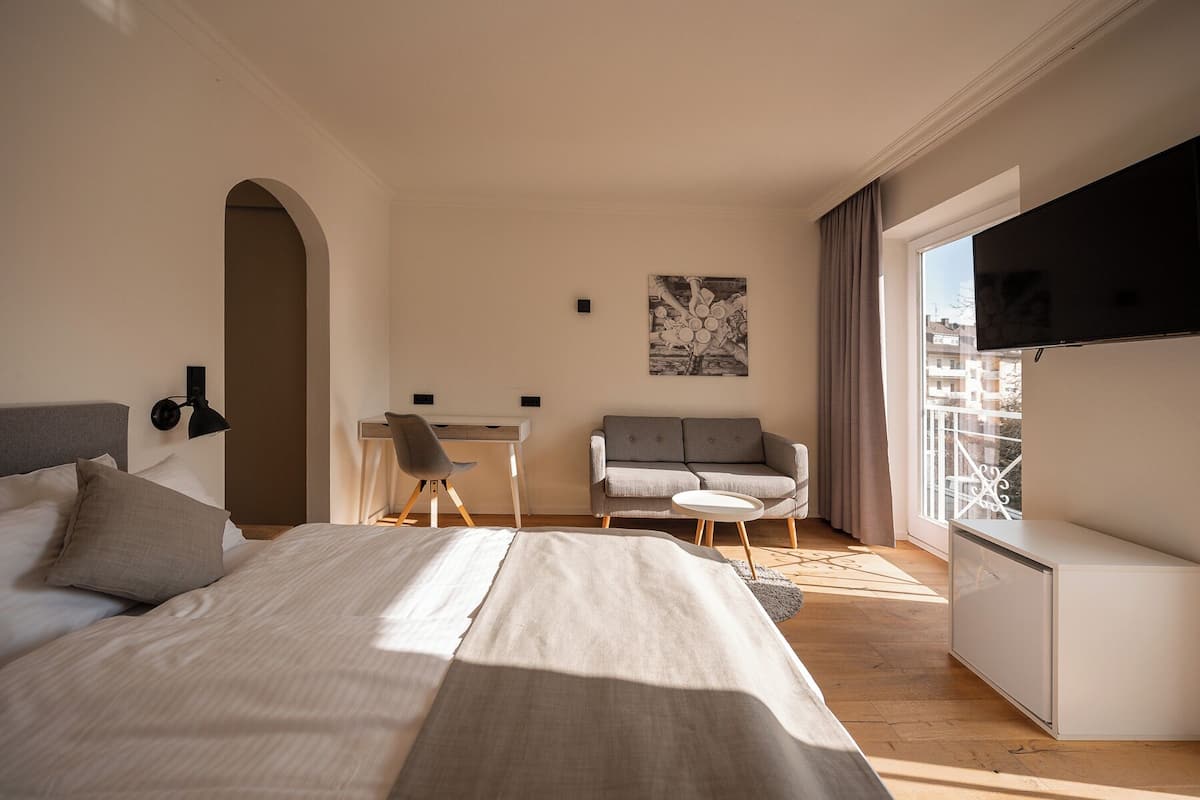 Una habitación de hotel moderna con cama, escritorio, silla, sofá y televisión.